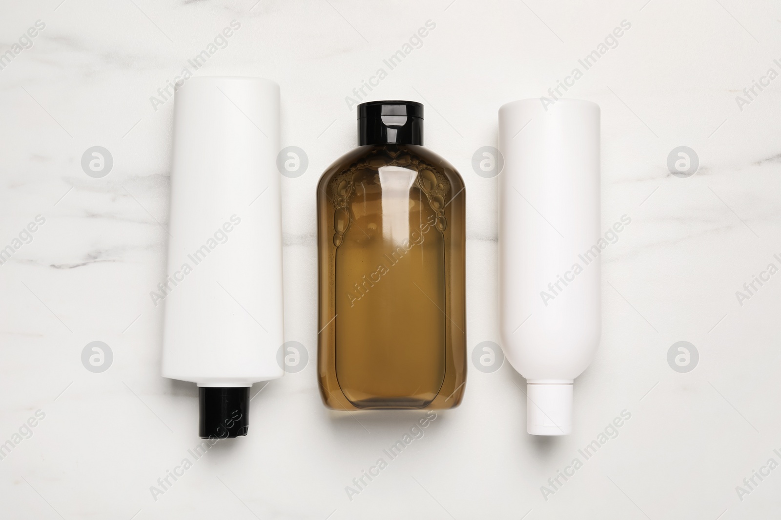 Photo of Shampoo bottles on white marble table, flat lay