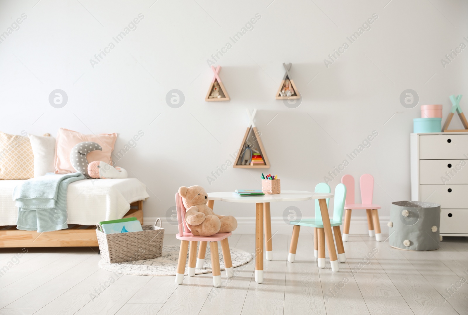 Photo of Small table and chairs with bunny ears in children's room interior