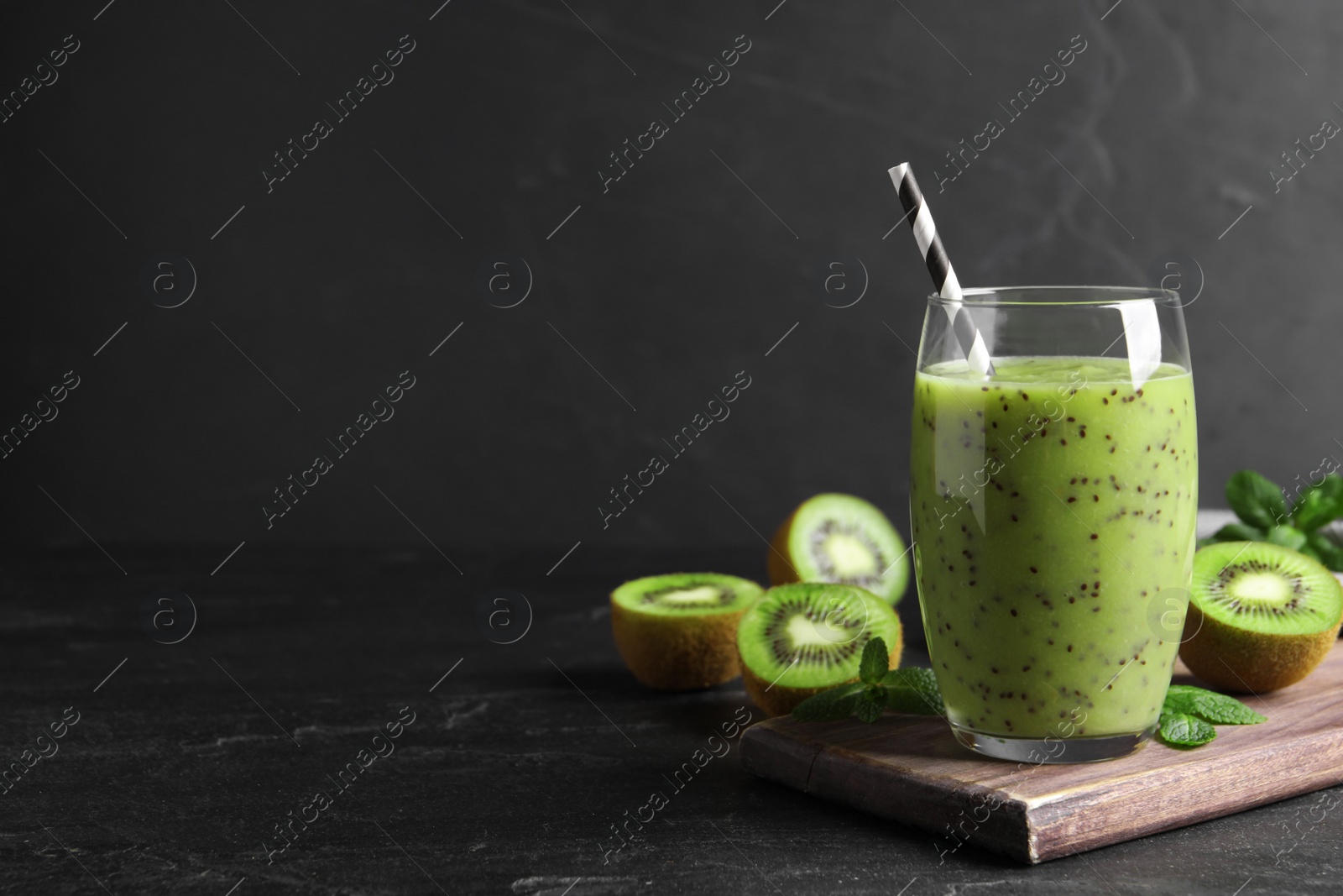 Photo of Delicious kiwi smoothie and fresh ingredients on black table, space for text