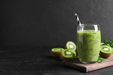 Delicious kiwi smoothie and fresh ingredients on black table, space for text