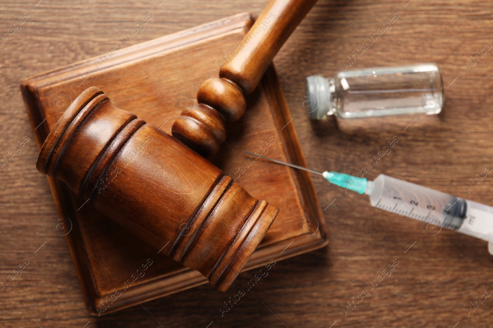 Photo of Law concept. Gavel, syringe and glass vial on wooden table, top view