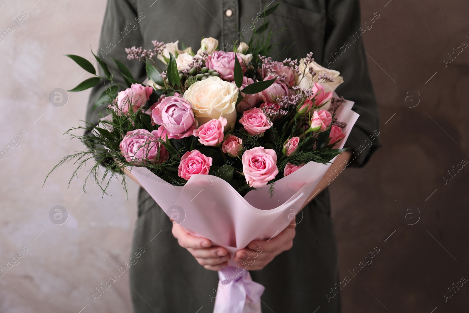 Photo of Woman with bouquet of beautiful roses on beige background, closeup
