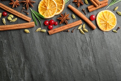 Different mulled wine ingredients on black slate table, flat lay. Space for text