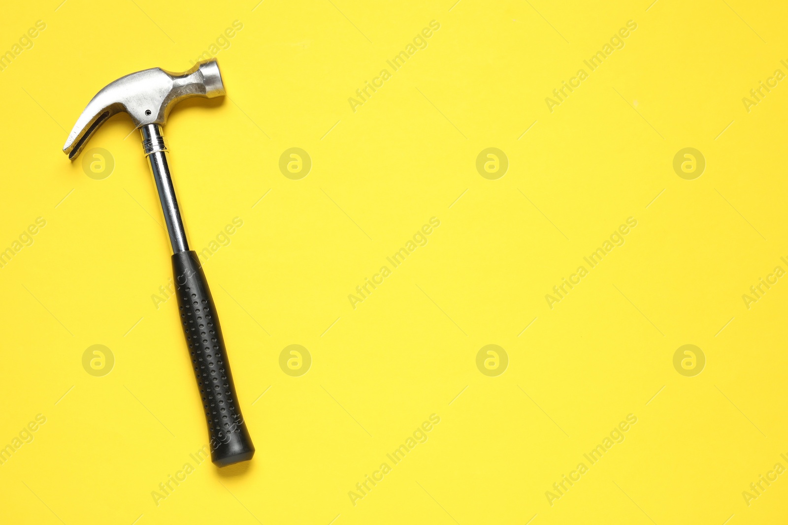 Photo of Hammer on yellow background, top view. Space for text