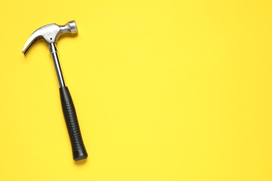 Photo of Hammer on yellow background, top view. Space for text