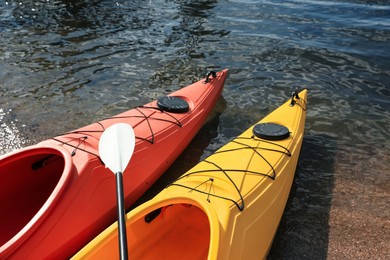 Photo of Modern kayaks with paddle on river, closeup. Summer camp activity
