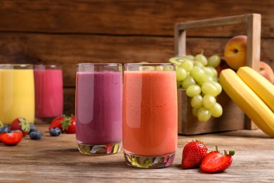 Photo of Glasses with different tasty smoothies and ingredients on wooden table