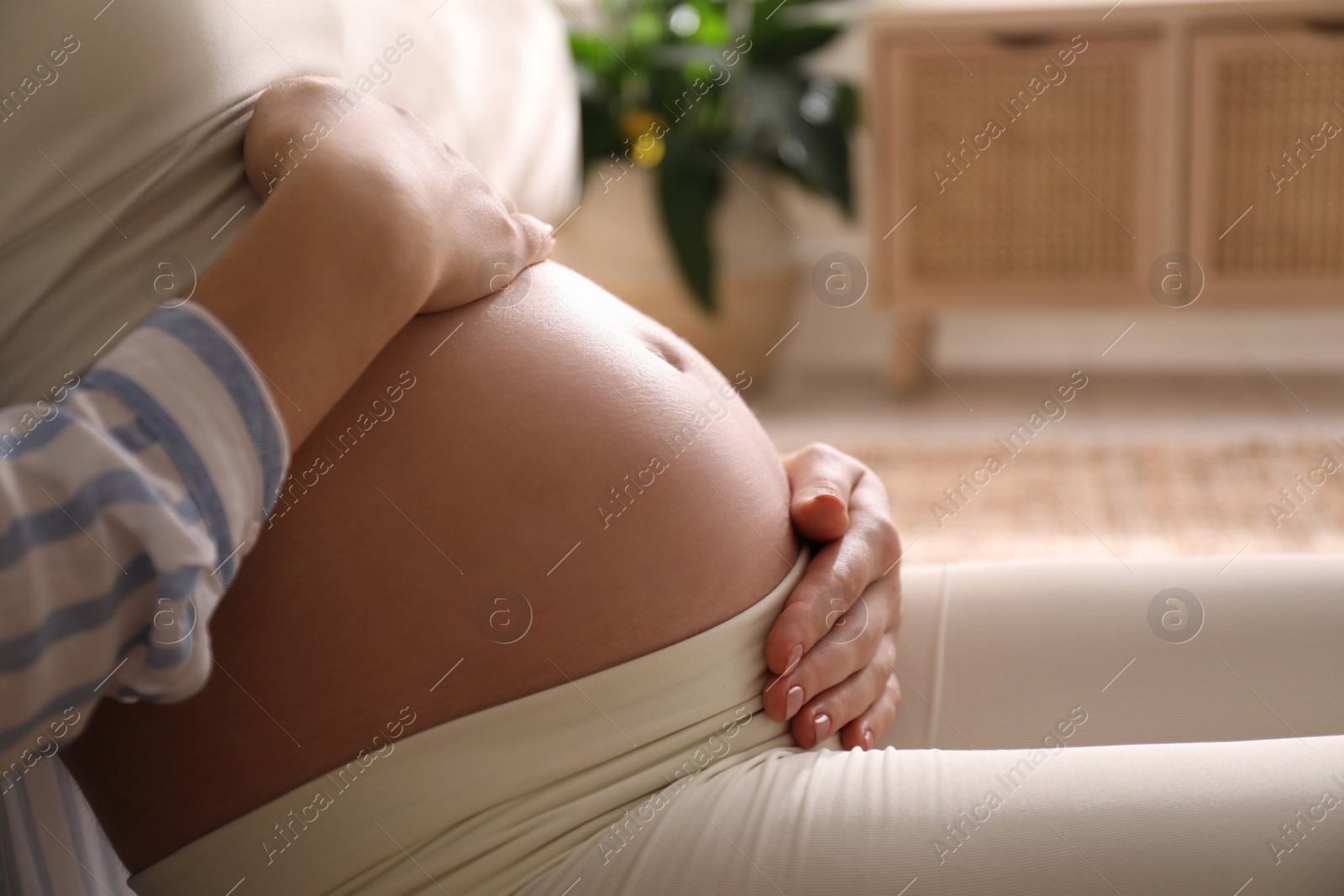 Photo of Pregnant young woman touching belly at home, closeup