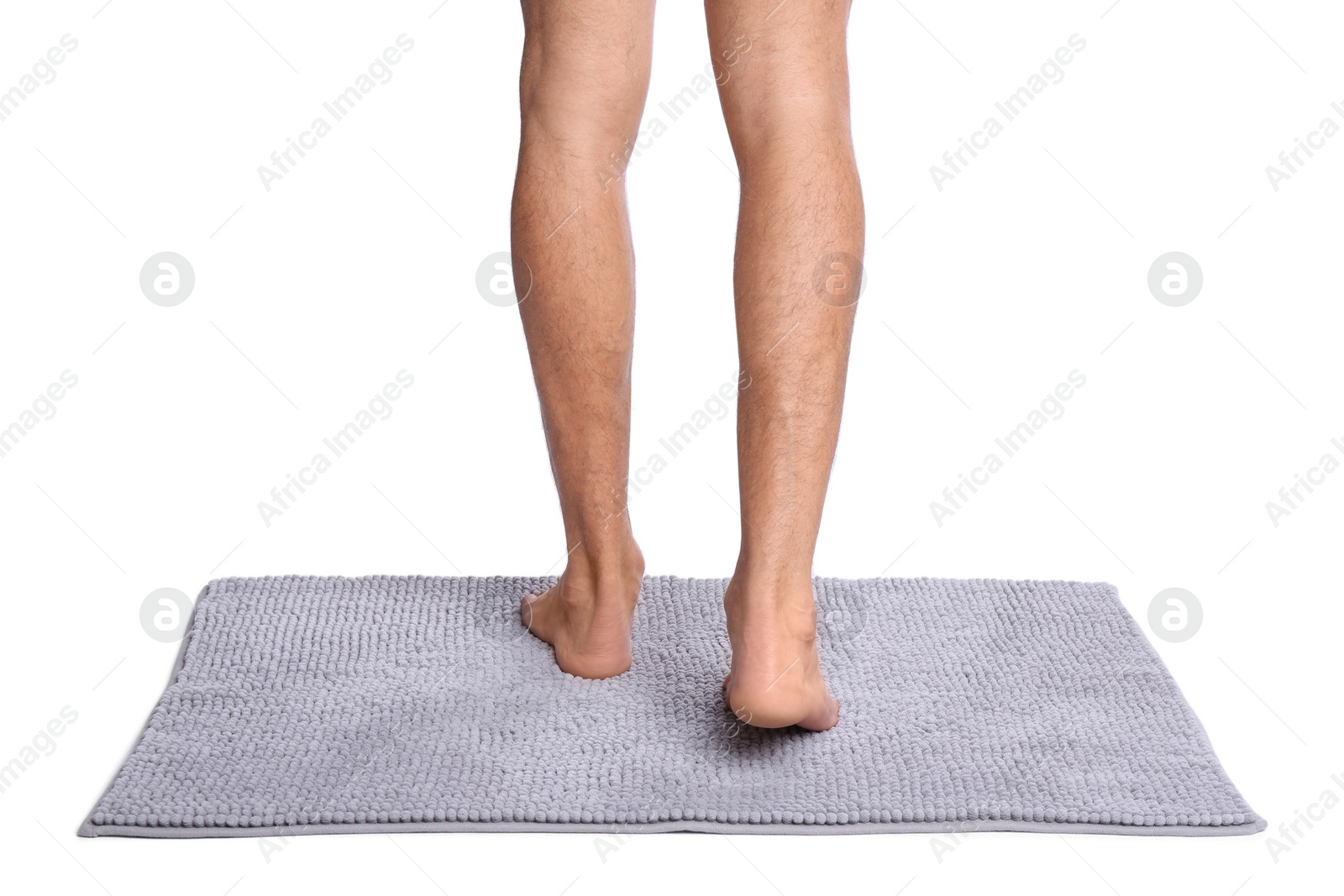 Photo of Man standing on soft grey bath mat against white background, closeup