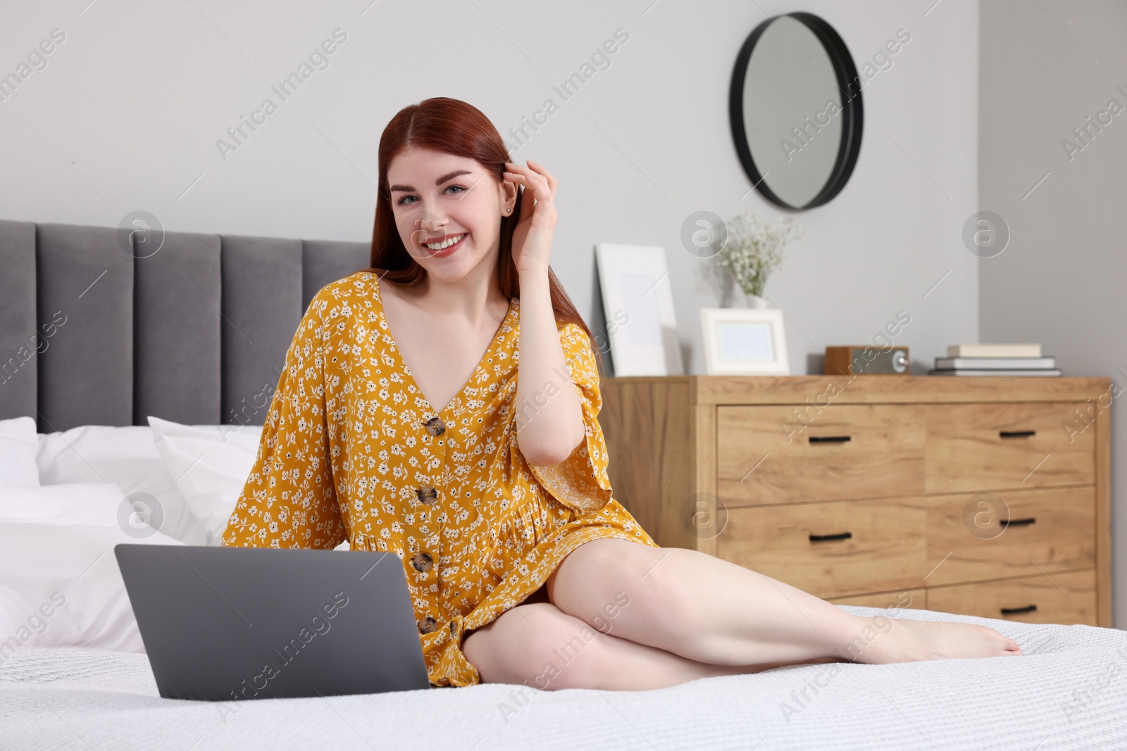 Photo of Happy woman with laptop on bed in bedroom