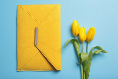 Photo of Flat lay composition with stylish woman's clutch and spring flowers on color background