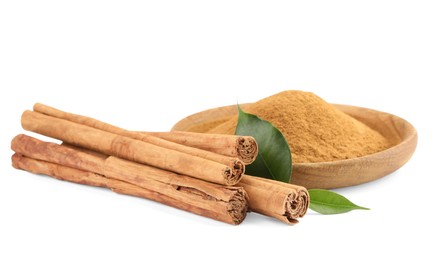 Photo of Dry aromatic cinnamon sticks, powder and green leaves isolated on white