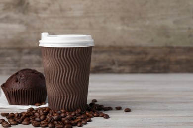 Photo of Paper cup with white lid, coffee beans and muffin on wooden table, space for text. Coffee to go