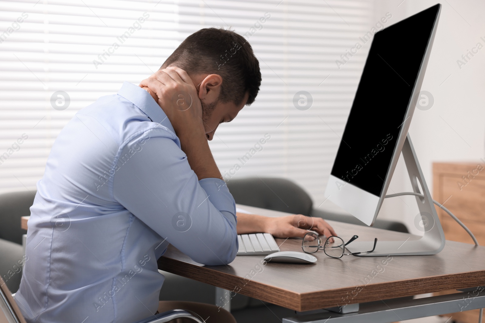 Photo of Man suffering from neck pain in office