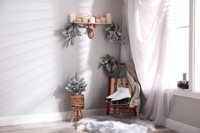 Pair of ice skates, sleigh and beautiful Christmas decor near window indoors, space for text