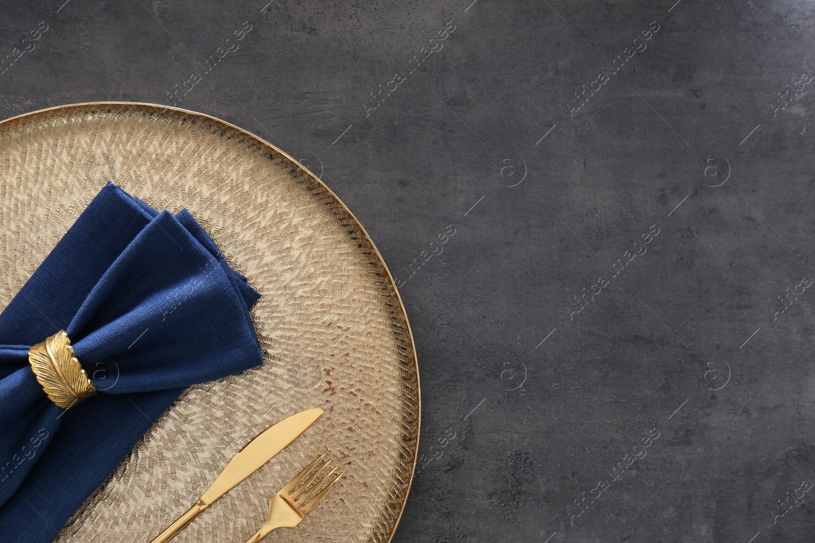 Photo of Tray with blue napkins, decorative ring and cutlery on grey table, top view. Space for text