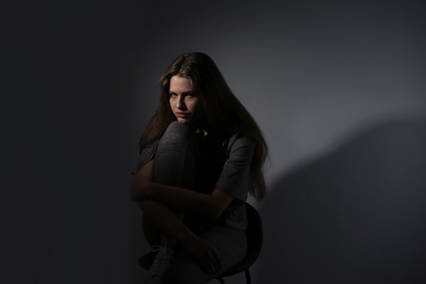 Depressed young woman on gray background