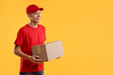 Happy courier with parcel on yellow background. Space for text