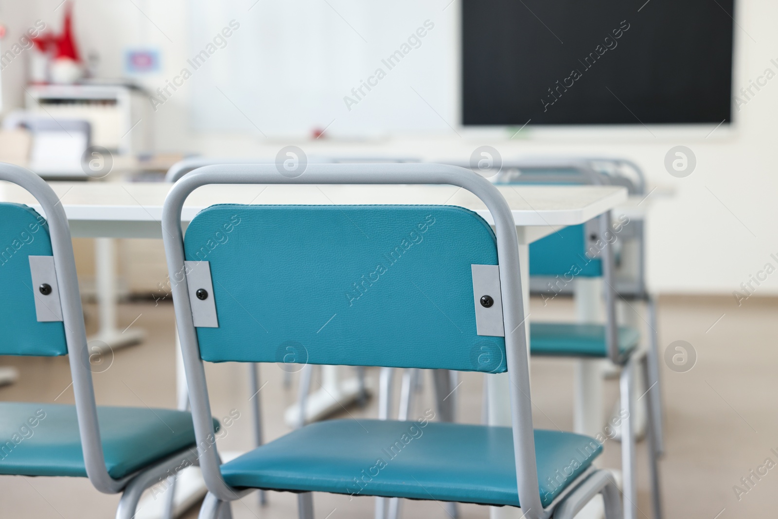 Photo of Empty school classroom with desks, blackboard and chairs