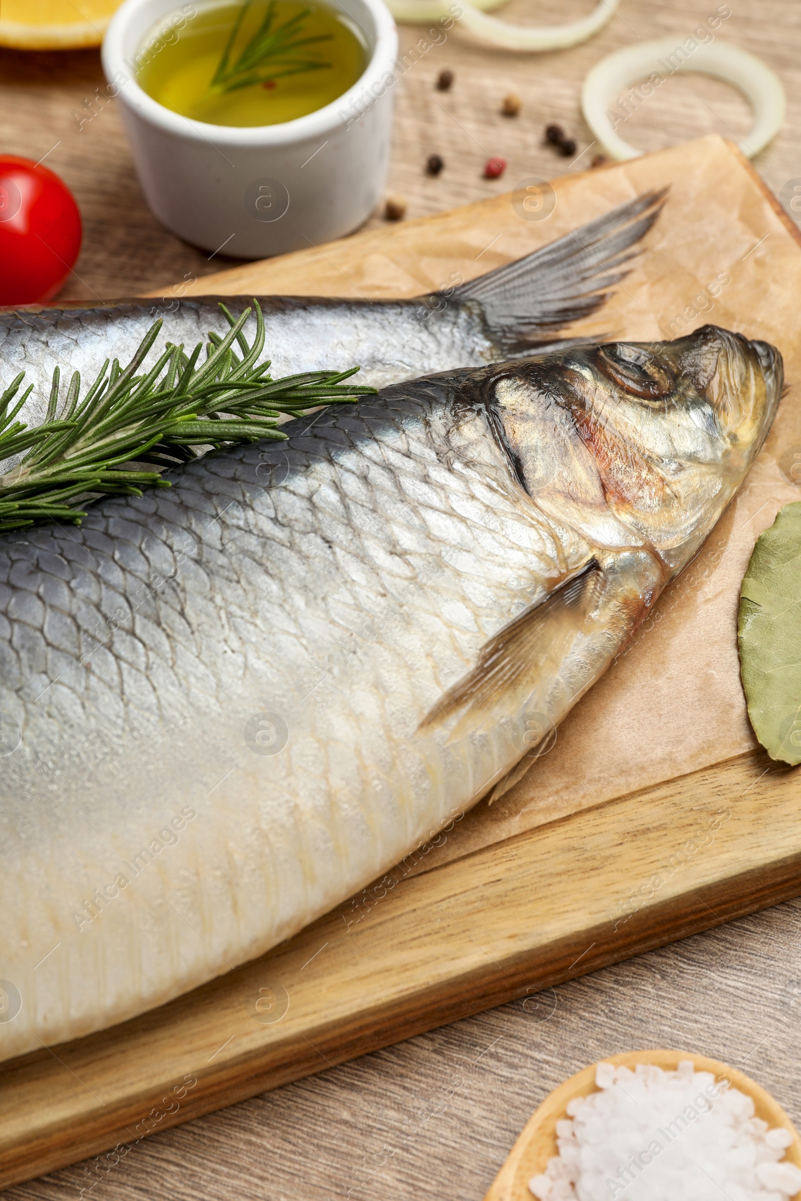 Photo of Delicious salted herrings and ingredients on wooden table, closeup