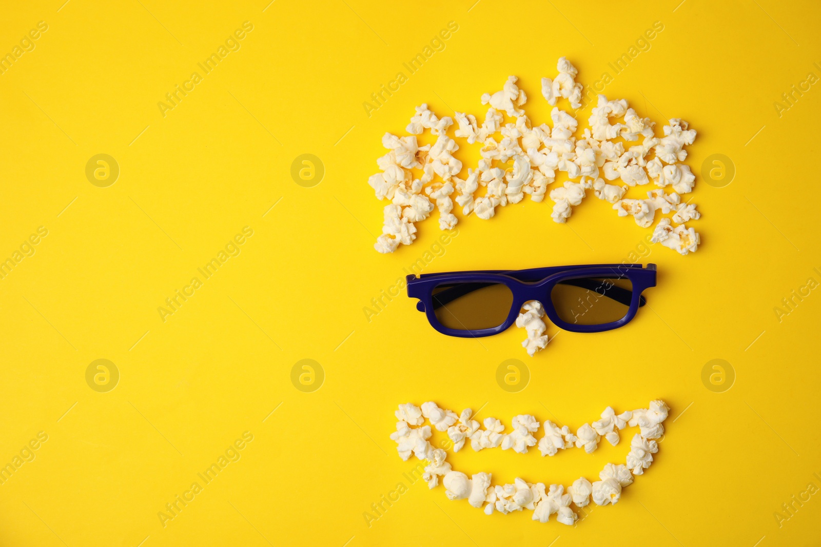 Photo of Face made of popcorn and glasses on color background, top view with space for text. Cinema snack