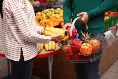 Photo of Couple with shopping basket in supermarket, closeup