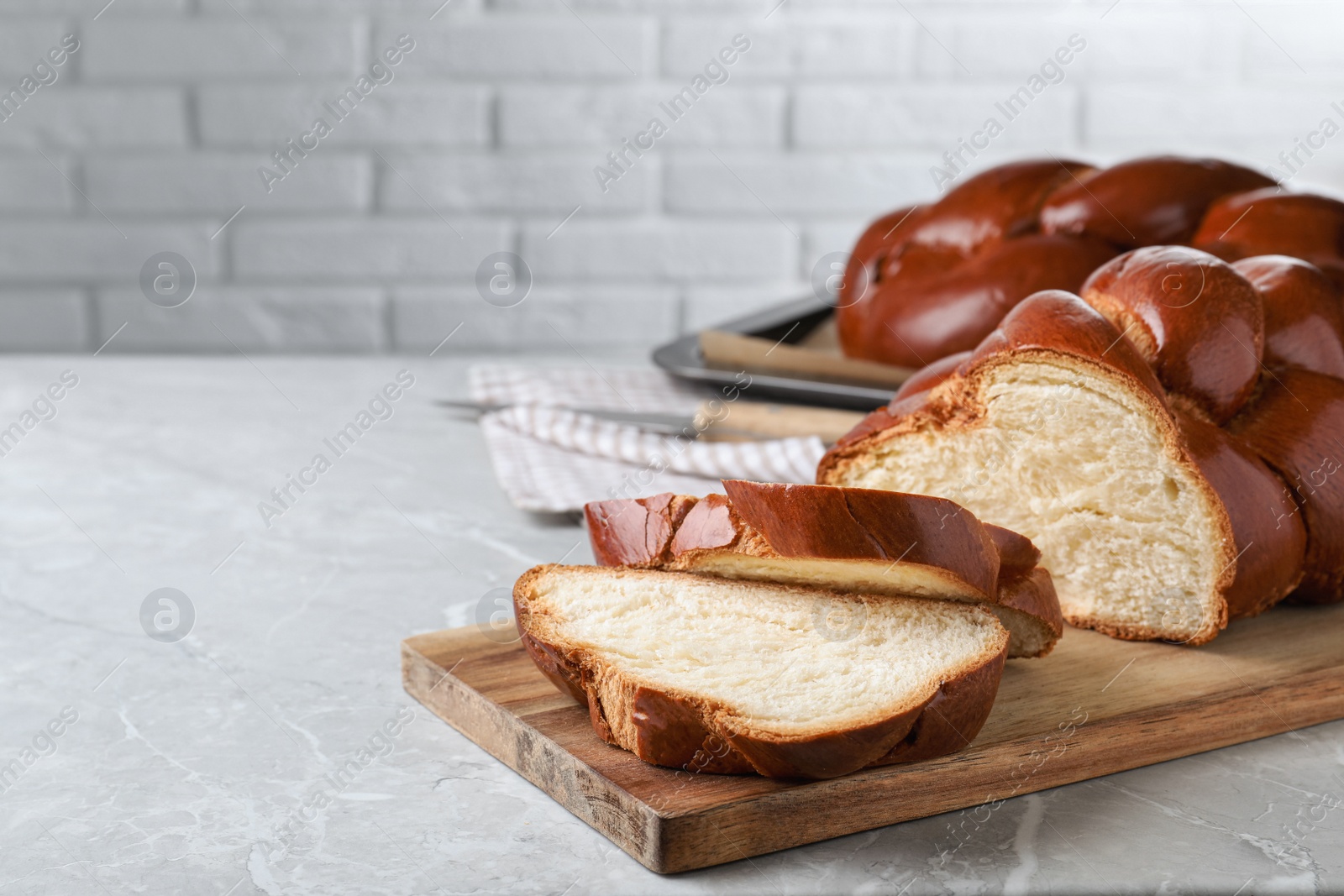 Photo of Cut homemade braided bread on grey table, space for text. Traditional Shabbat challah