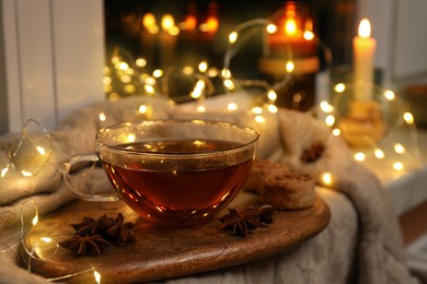 Photo of Glass cup of aromatic anise tea on wooden board indoors, bokeh effect