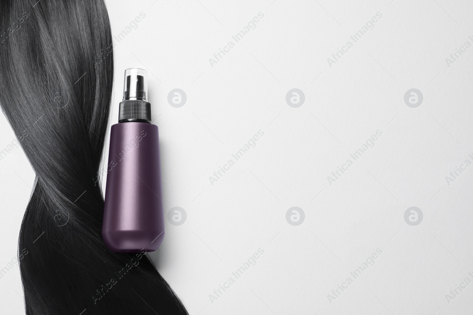 Photo of Spray bottle with thermal protection and lock of brunette hair on light background, flat lay. Space for text