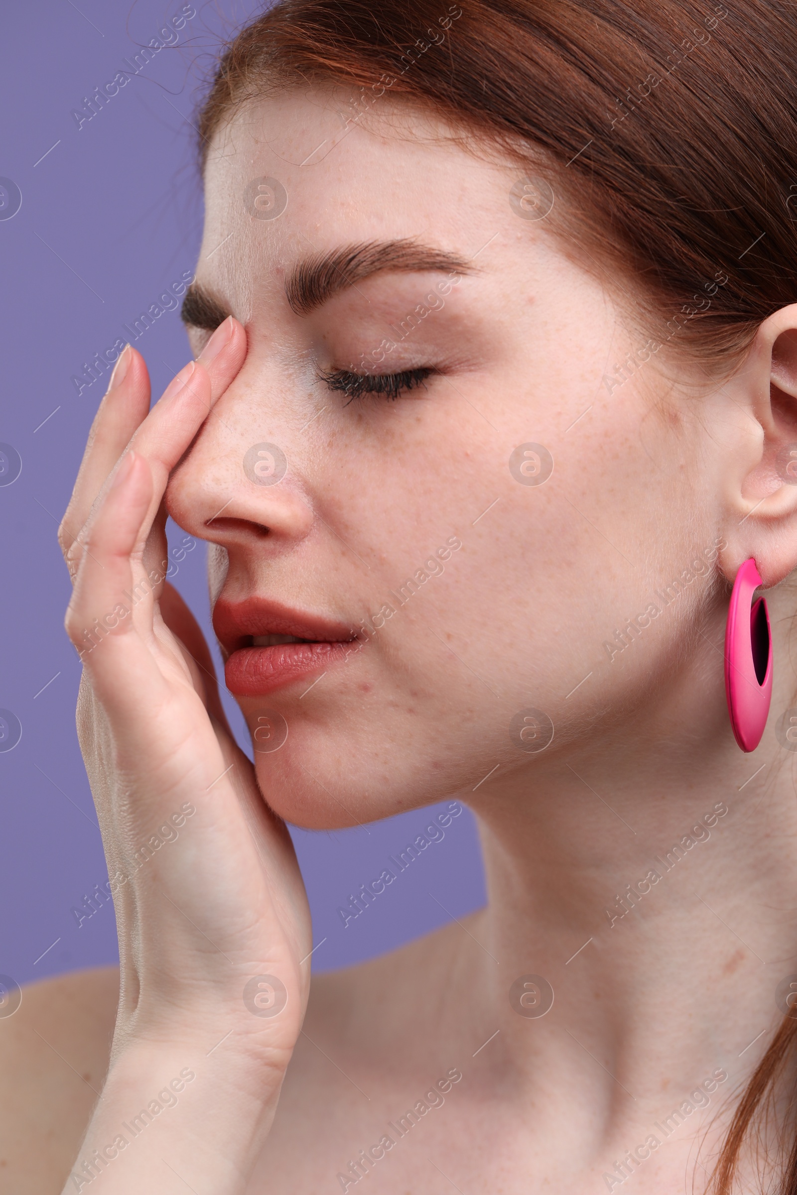 Photo of Beautiful woman with freckles on purple background, closeup