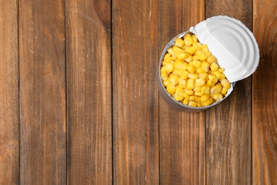 Photo of Tin can with conserved corn on wooden background, top view