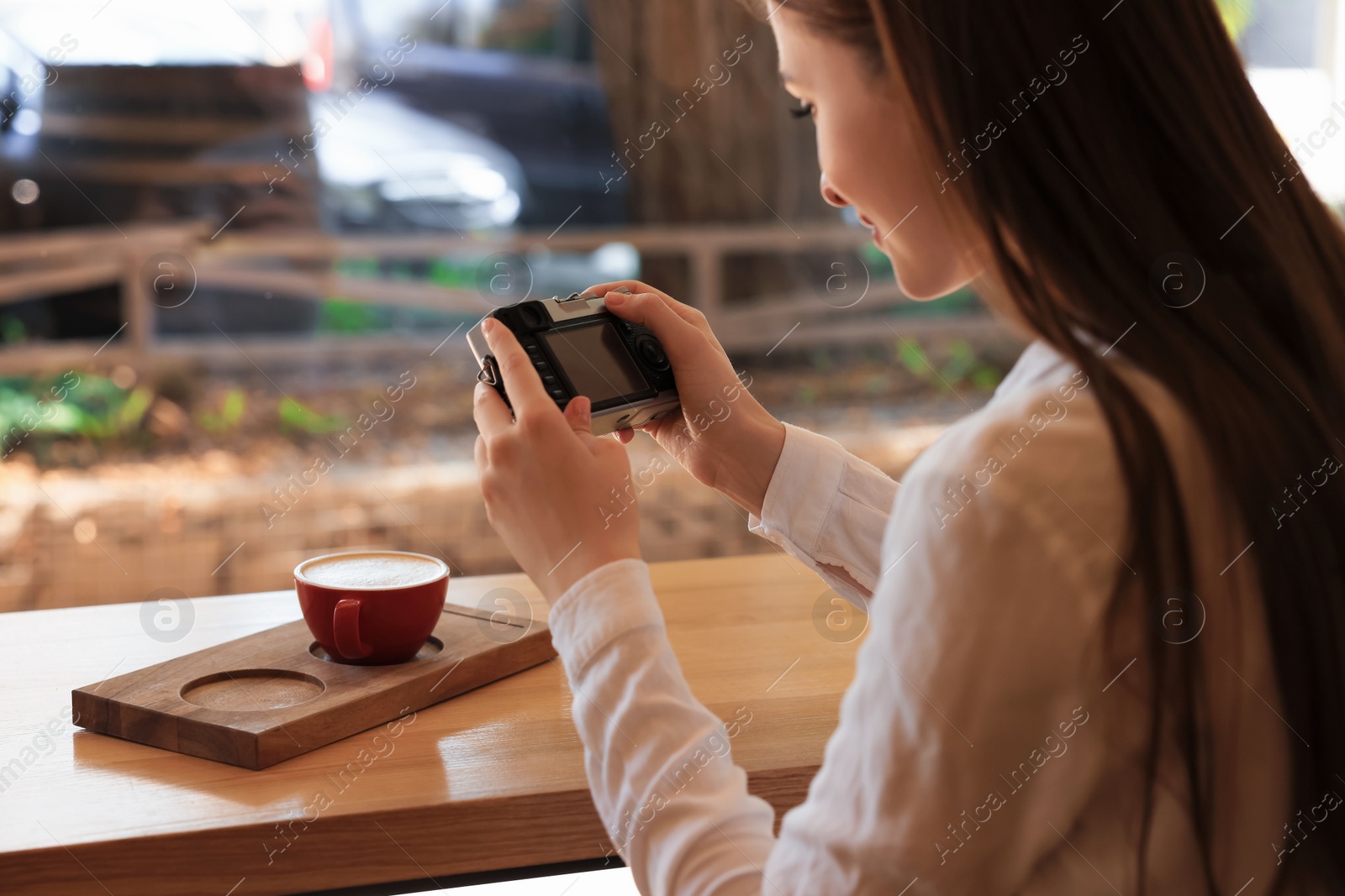 Photo of Woman taking photo of cup with coffee indoors, closeup. Creative hobby
