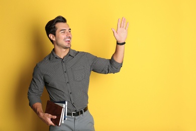 Photo of Young male teacher with books on yellow background. Space for text