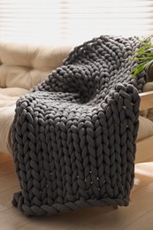 Dark grey chunky knitted blanket on beige sofa in living room