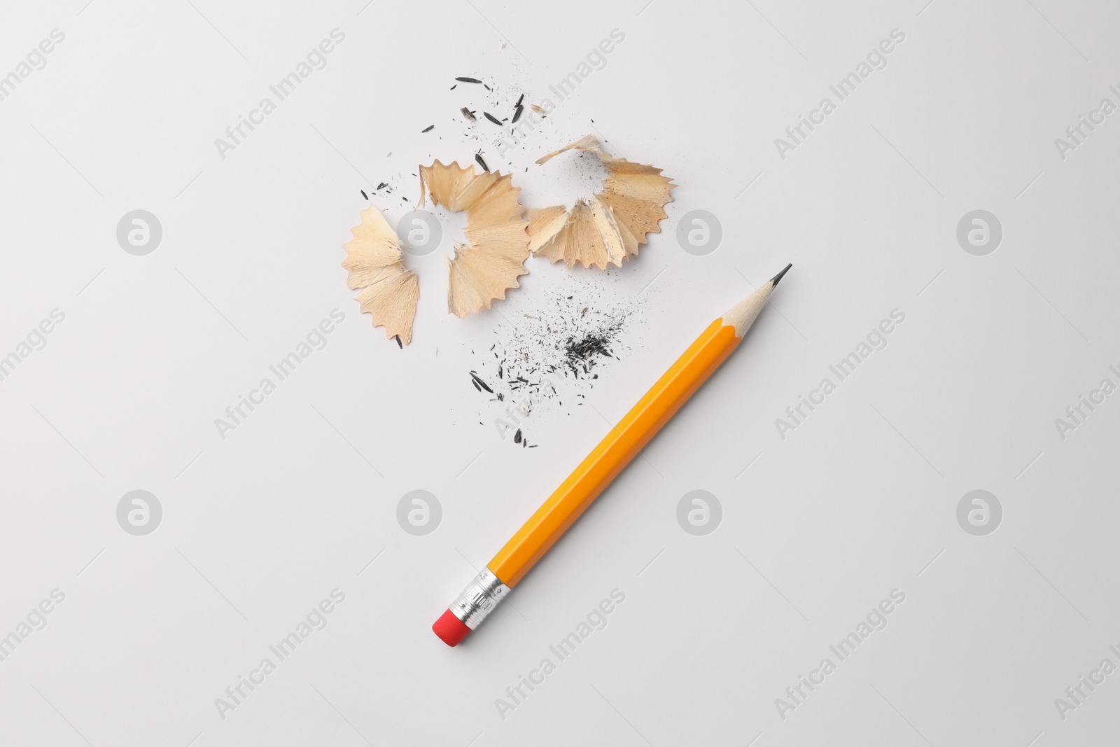 Photo of Graphite pencil and shavings on white background, flat lay