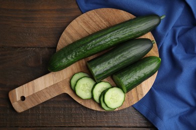 Photo of Fresh whole and cut cucumbers on wooden table, top view