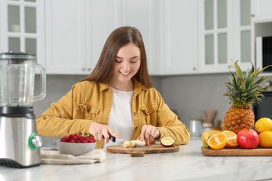 Photo of Woman preparing ingredients for tasty smoothie at white marble table in kitchen