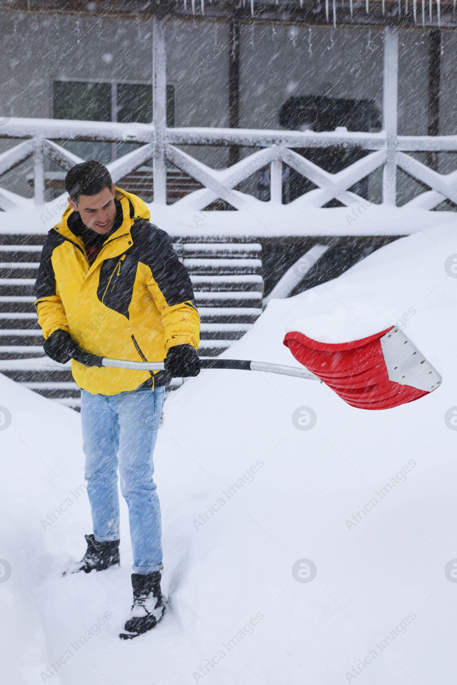 Photo of Man cleaning snow with shovel near house