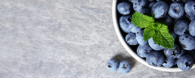 Image of Tasty fresh blueberries on grey table, top view with space for text. Banner design