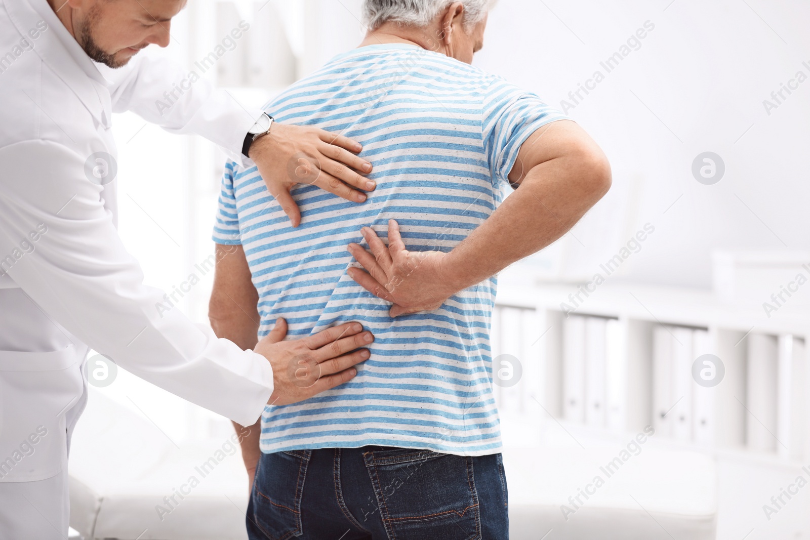 Photo of Chiropractor examining patient with back pain in clinic