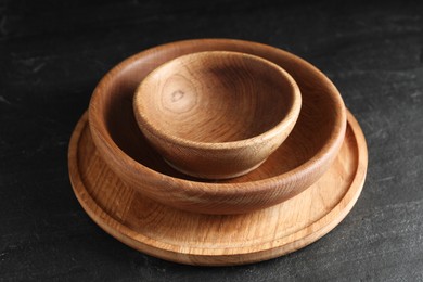 Photo of Empty clean wooden dishware on black table, closeup