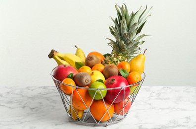 Photo of Metal bowl with different fresh fruits on white marble table