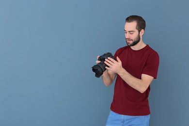 Photo of Young photographer with professional camera on color background