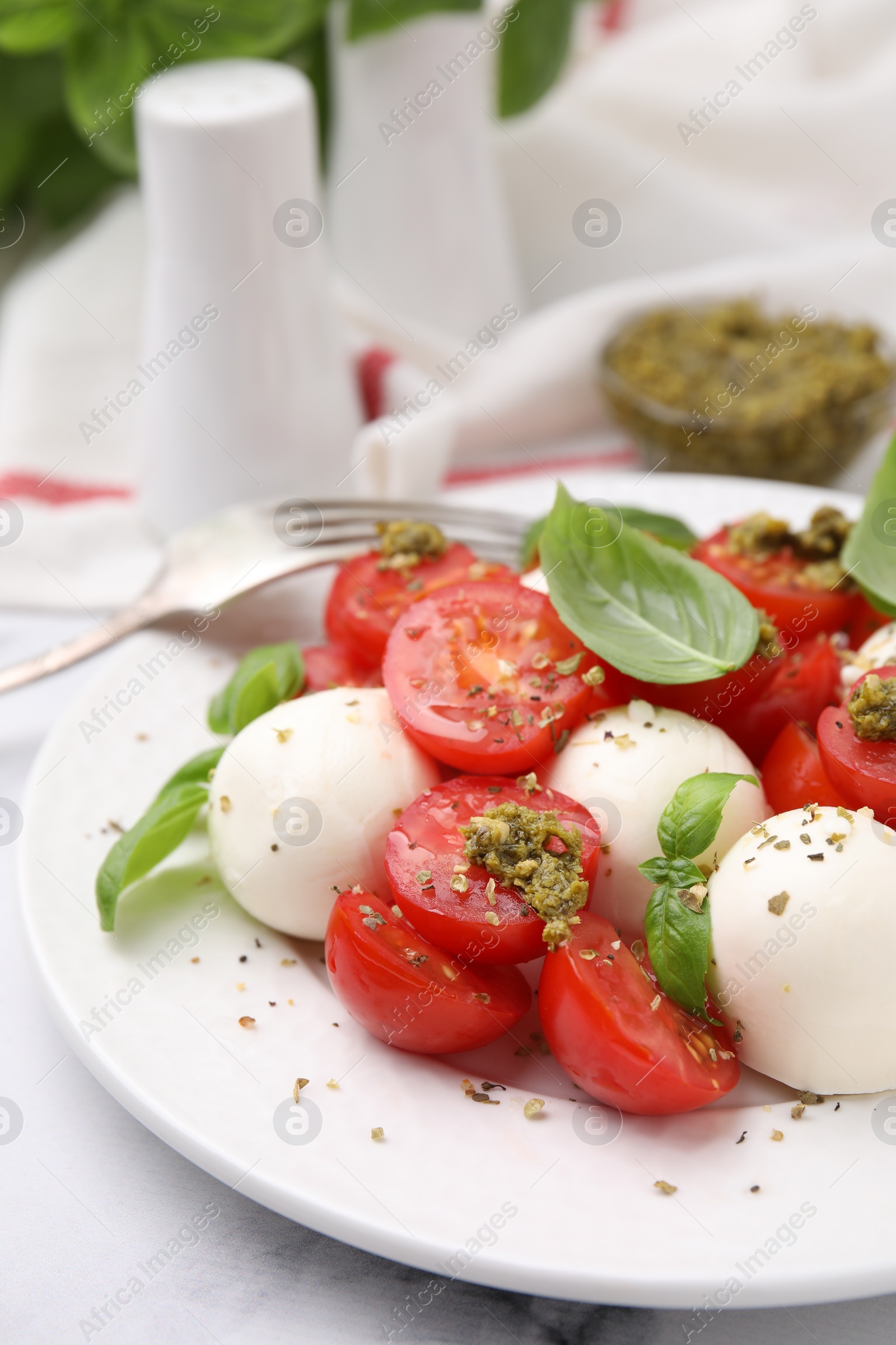 Photo of Tasty salad Caprese with tomatoes, mozzarella balls and basil served on table, closeup