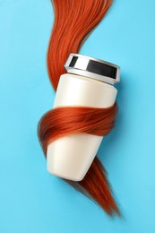 Bottle wrapped in lock of hair on light blue background, top view. Natural cosmetic product