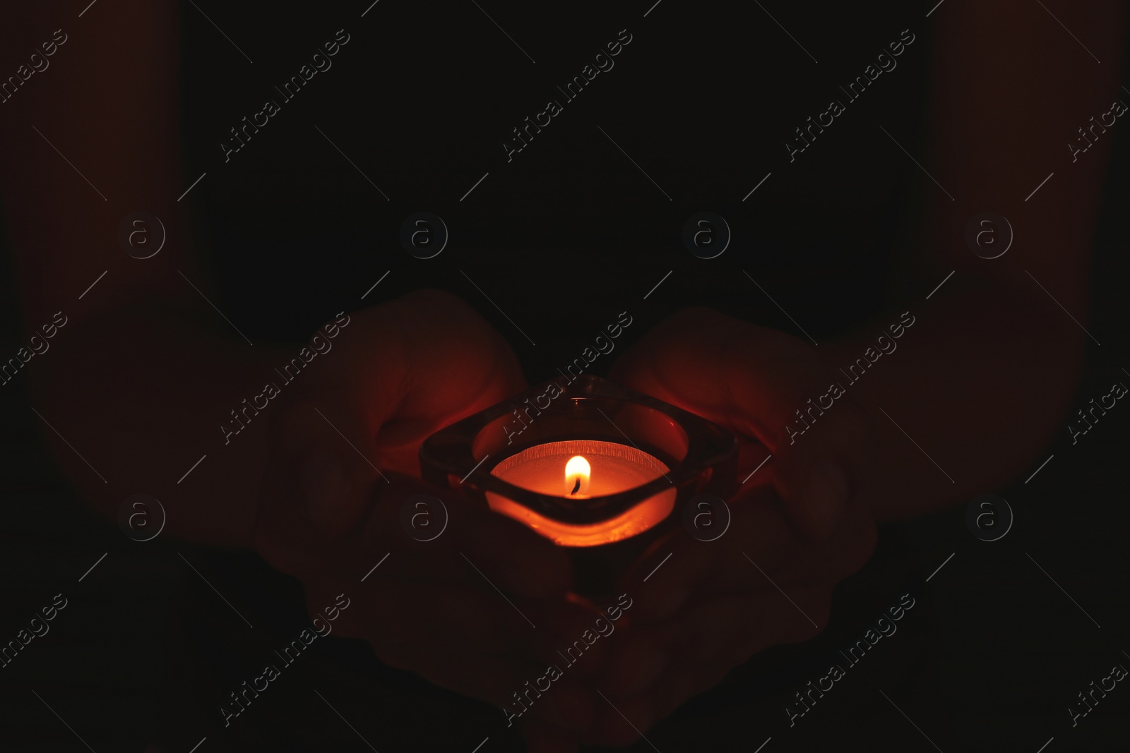 Photo of Person holding burning candle in darkness, closeup