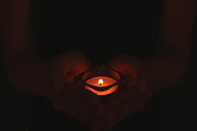 Photo of Person holding burning candle in darkness, closeup