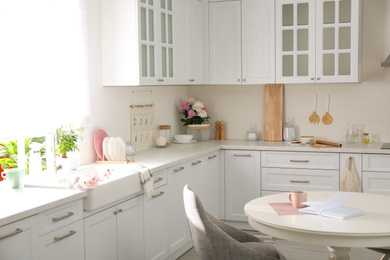 Photo of Book and cup on white table in modern kitchen. Interior design