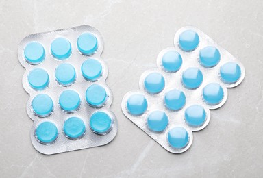 Photo of Blisters with blue cough drops on grey background, flat lay
