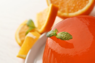 Photo of Tasty orange jelly with mint on table, closeup. Space for text